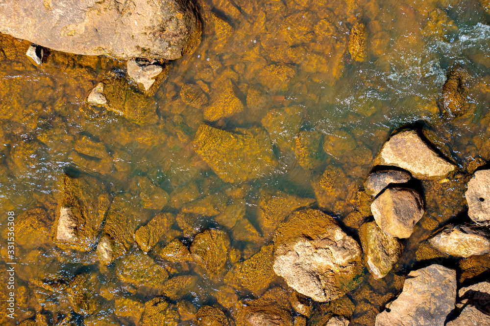 A background texture of a river flowing over brown rocks