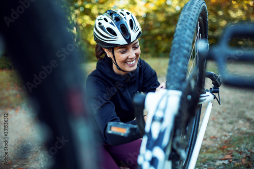 Foto Female cyclist fixing bike outdoor