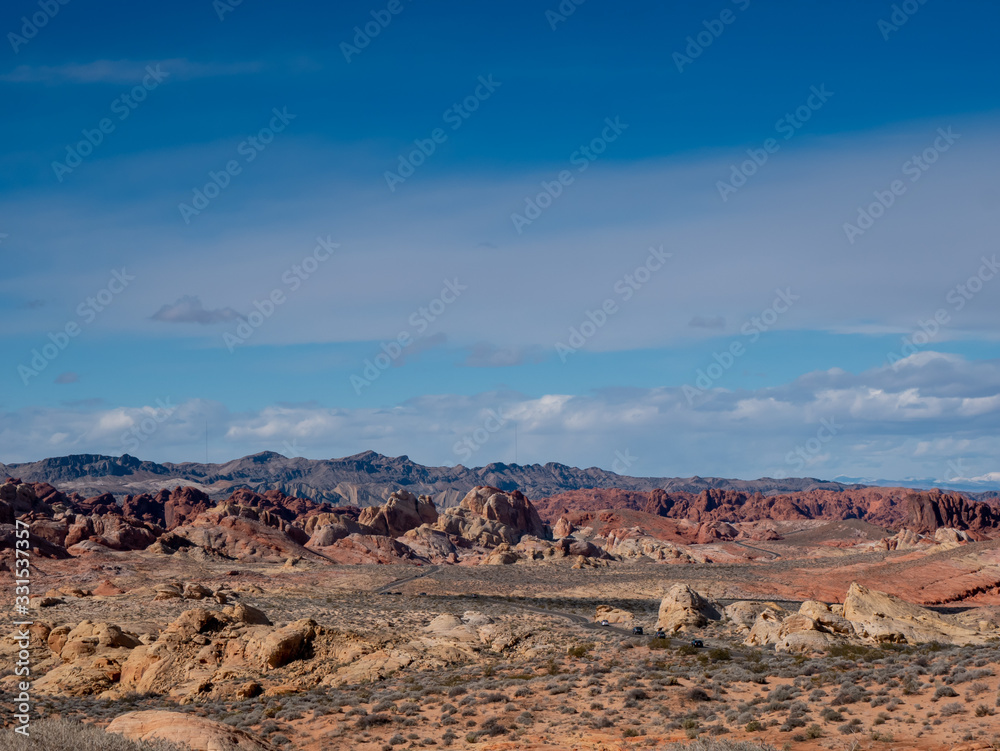 Fototapeta premium Blue sky over a road through beautiful rugged desert terrain at Valley of Fire State Park, Nevada, USA.