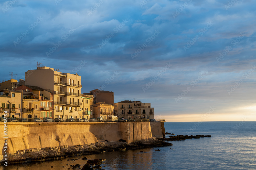 Coastline of Ortigia island at sunrise with cloudscape in province of Syracuse in Sicily, south Italy