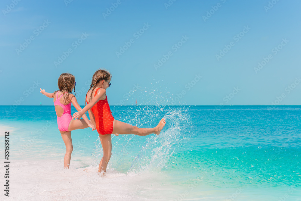 Little happy funny girls have a lot of fun at tropical beach playing together.