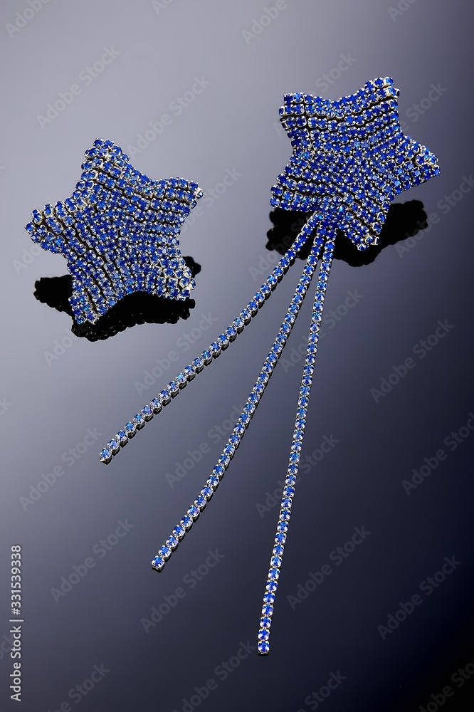 Obraz premium Plastic jewelry earrings with crystals and stones for women on a dark background.