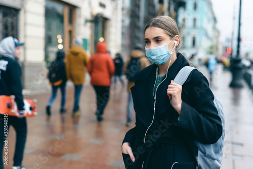 Prevention of coronavirus outbreak in 2020. Portrait of young european woman wearing a mask in the city street. Prevent pollution and disease concept.