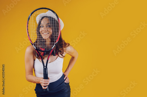 In front of a lady, looking at a tennis racket, with a hat on her head and a smile © Kantemir Production