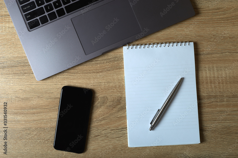 Remote work laptop phone notepad with pen on the table Remote work laptop phone notepad with pen on the table