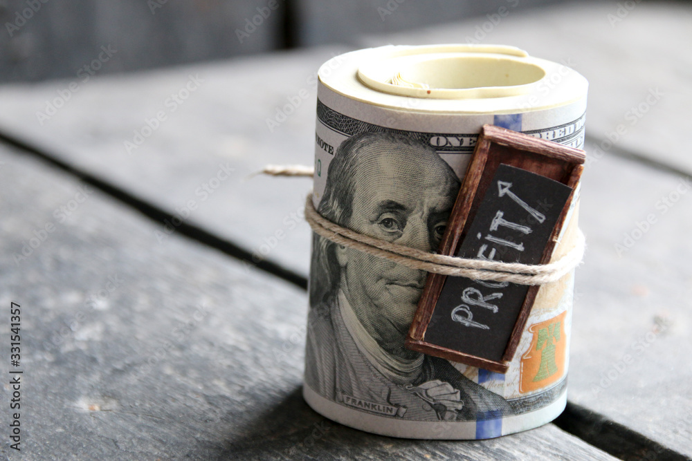 Profit concept. A roll of dollar bills and an inscription with an arrow. Profit concept. A roll of dollar bills and an inscription with an arrow.