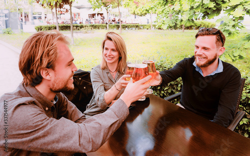 Smiling young friends clanging glasses of beer photo