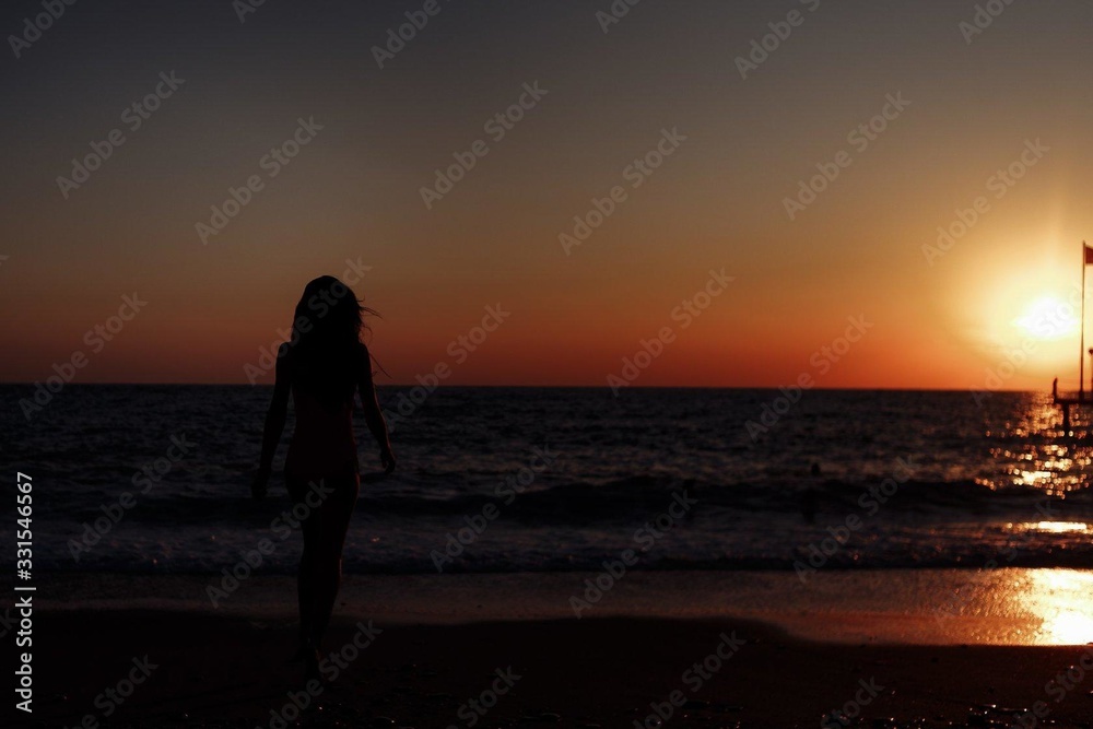silhouette of an unknown girl at sunset by the sea
