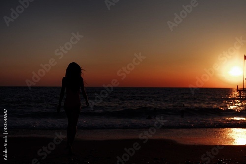 silhouette of an unknown girl at sunset by the sea