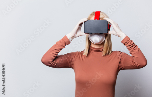 Style blonde woman in face mask with VR glasses on white background