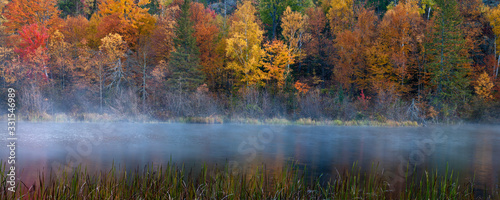 A panoramic view of the fall colors and mist rising at sunrise along the Michigamme River in Michigan s Upper Peninsula.