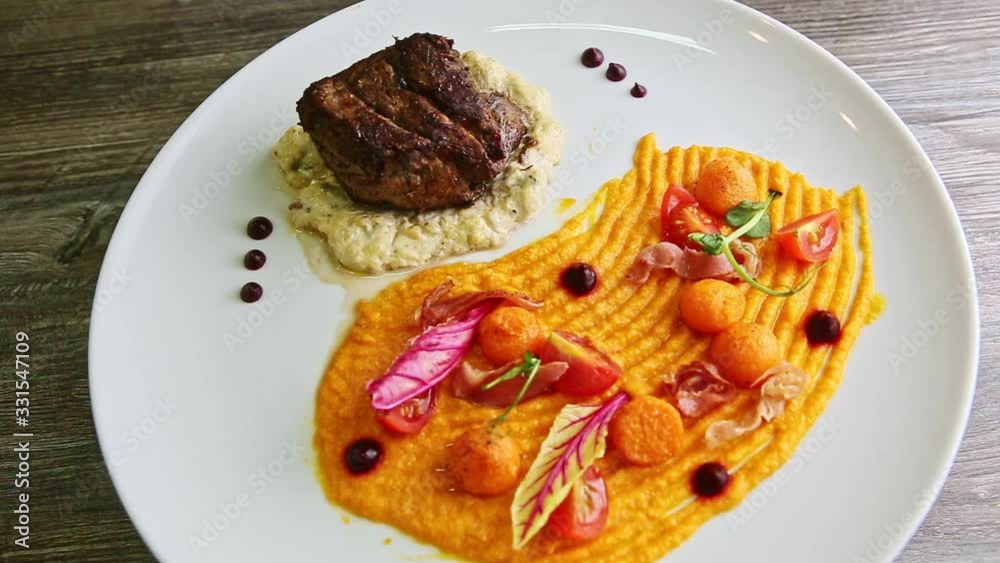 top view on big piece of roasted meat with finely decorated garnish rotates on plate top view on big piece of roasted meat with finely decorated garnish rotates on plate
