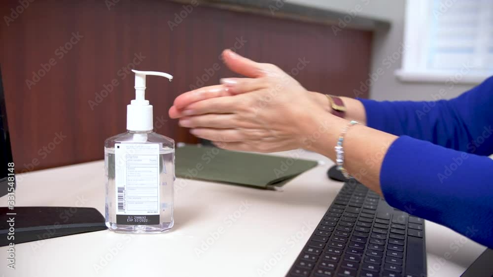 392 Secretary cleaning hands with hands sanitizer at her desk 392 Secretary cleaning hands with hands sanitizer at her desk