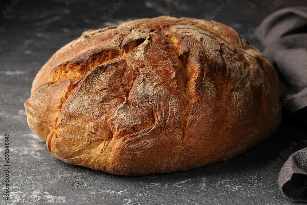Round, freshly baked bread, made from rye flour, on a gray background, close-up.A loaf of bread.