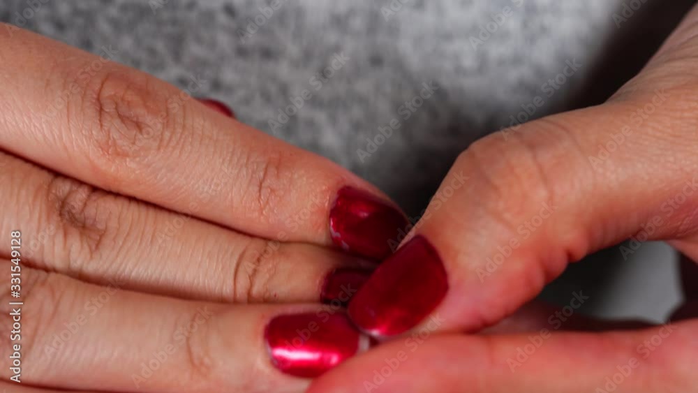 Close up of woman's hands picking her nails. Female strips red nail polish off her nails with her fingers from stress. Close up of woman's hands picking her nails. Female strips red nail polish off her nails with her fingers from stress.