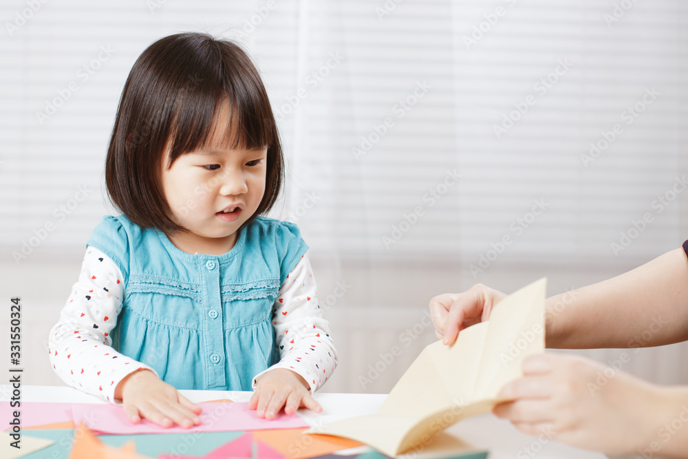 toddler girl learn making Origami at home against white background toddler girl learn making Origami at home against white background