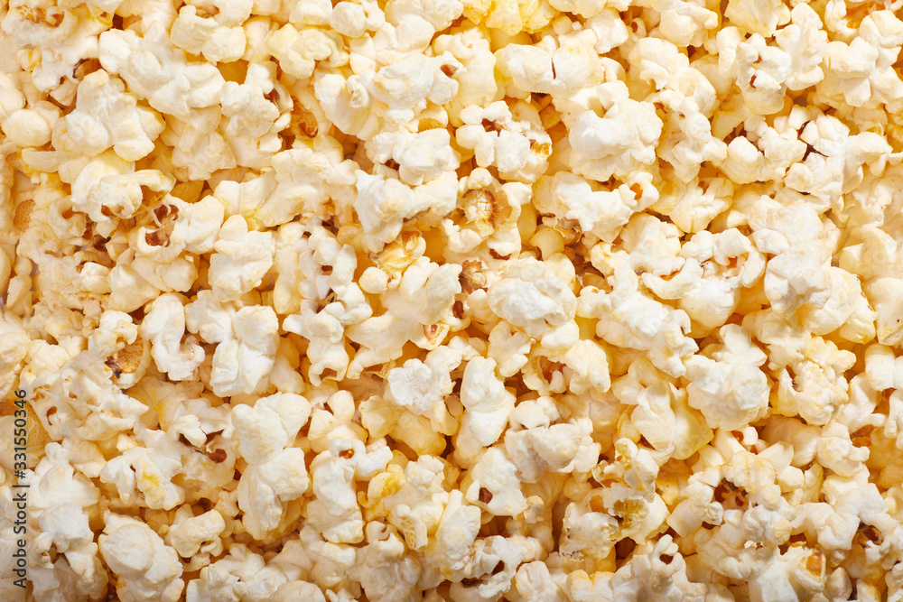 Flatlay of salted popcorn with cheese. Heap of homemade delicious popcorn on a rustic wooden table. Snacks and food for a movie theater or cinema. Fastfood background.  Strip texture