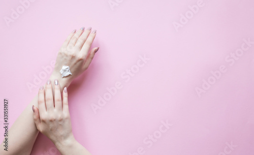 Natural Cosmetics for hand skin care with cream bottle, a means to reduce wrinkles on hands, moisturizing. Beautiful woman's hands on the pastel  pink background.