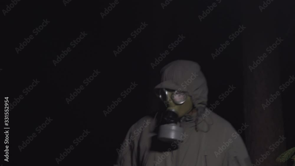 man in a gas mask escapes from coronavirus in the woods at night
