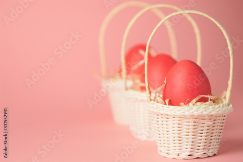 Pink chicken eggs in a white wicker basket covered with straw a bright pink background. Holiday card with space for text.Easter symbol.Copy space.