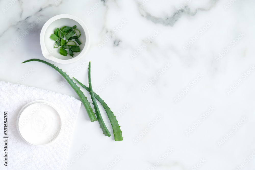Aloe vera natural organic cosmetic cream moisturizer and sliced stems aloe vera on marble background. Flat lay, top view. Beauty product for face and hand skincare Aloe vera natural organic cosmetic cream moisturizer and sliced stems aloe vera on marble background. Flat lay, top view. Beauty product for face and hand skincare