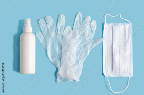 flat lay, top view, antiseptic, disinfector, medical gloves, mask - personal protective equipment and hygiene during the epidemic coronavirus on blue background