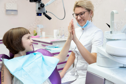 Smiling girl giving high five to dentist doctor. 