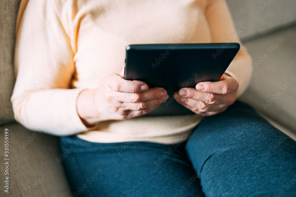 Obraz premium Old woman hands using a tablet. Old people with technology concept