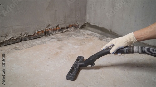 construction cleaning service sleeve anchor bolt . dust removal with vacuum cleaner. Worker vacuuming concrete floor