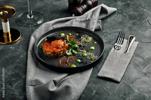 Fototapeta Naklejka Na Ścianę i Meble -  Fresh tartare with salmon, avocado, red caviar on a plate, beautiful serving, Beautiful serving, traditional Italian cuisine, gray background, copy space. food concept