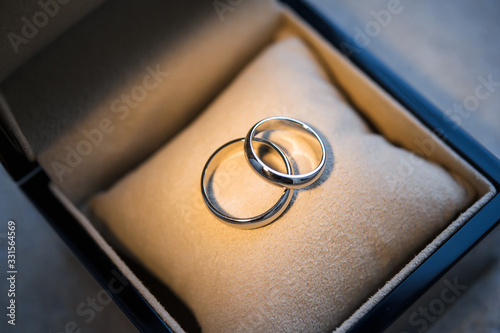 Two designer golden wedding rings with copy space and selective focus. Close-up view of white golden wedding rings in a box, before wedding ceremony and vows. Macro. 