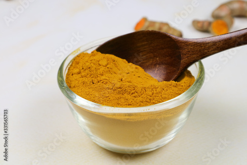 Turmeric powder in a separate glass cup on a white background is an ingredient in turmeric foods and ingredients in skin care products. Turmeric helps the skin to be strong.
