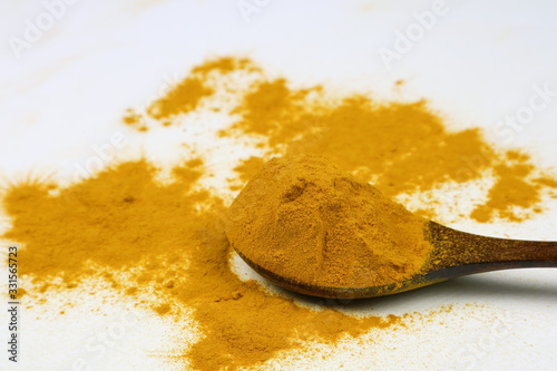 Turmeric powder in a wooden spoon isolated on a white background is an ingredient in turmeric foods and ingredients in skin care products. Turmeric helps the skin to be strong.