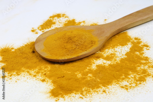 Turmeric powder in a wooden spoon isolated on a white background is an ingredient in turmeric foods and ingredients in skin care products. Turmeric helps the skin to be strong.