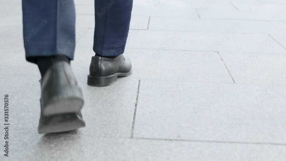 Businessman taking walk on street. Male executive wearing black shoes outside Businessman taking walk on street. Male executive wearing black shoes outside