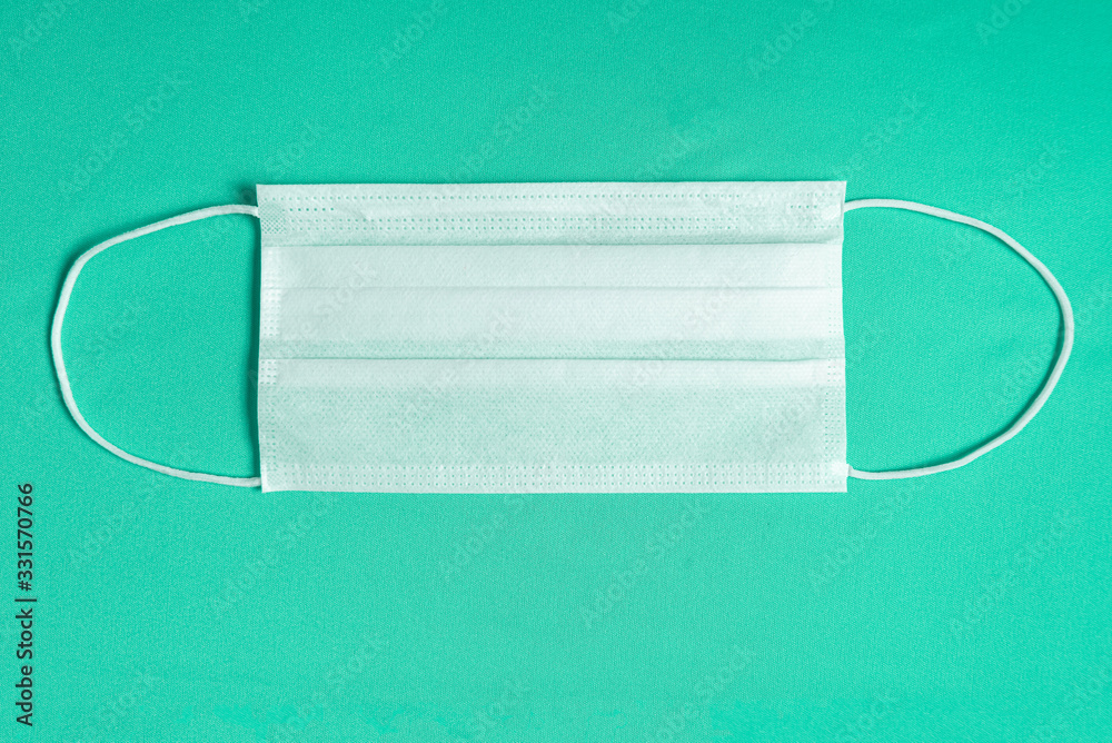 Surgical mask over minimalist green background Surgical mask over minimalist green background