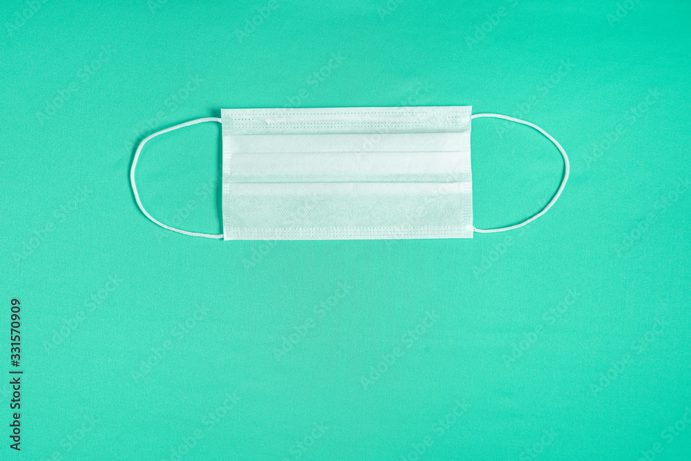 Surgical mask over minimalist green background Surgical mask over minimalist green background