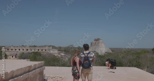 toma con personas de espalda en la cima de las piramides de uxmal