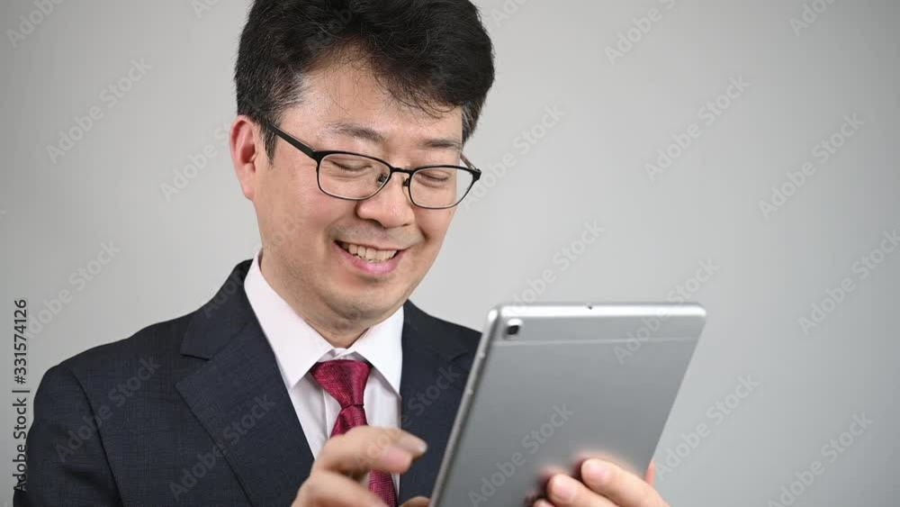 An Asian businessman who is using tablet to search for information or communicate. An Asian businessman who is using tablet to search for information or communicate.