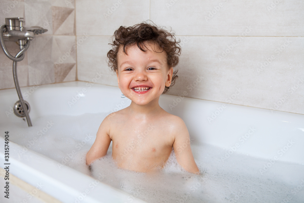 Happy boy child sitting in a bath with foam. Happy boy child sitting in a bath with foam.