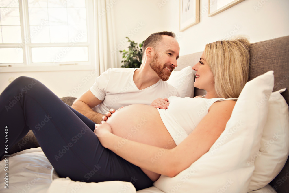 Beautiful pregnant woman and her handsome husband spending time together in bed Beautiful pregnant woman and her handsome husband spending time together in bed