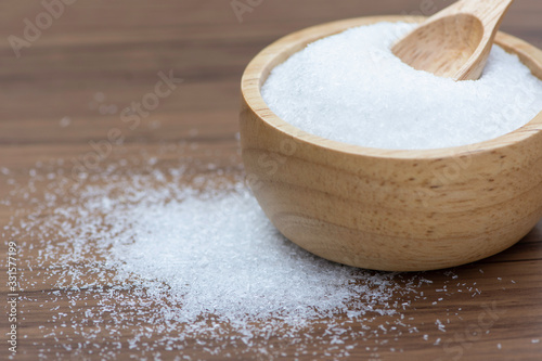 Monosodium glutamate ( MSG ) in wooden bowl isolated on wood table background. Selective focus.