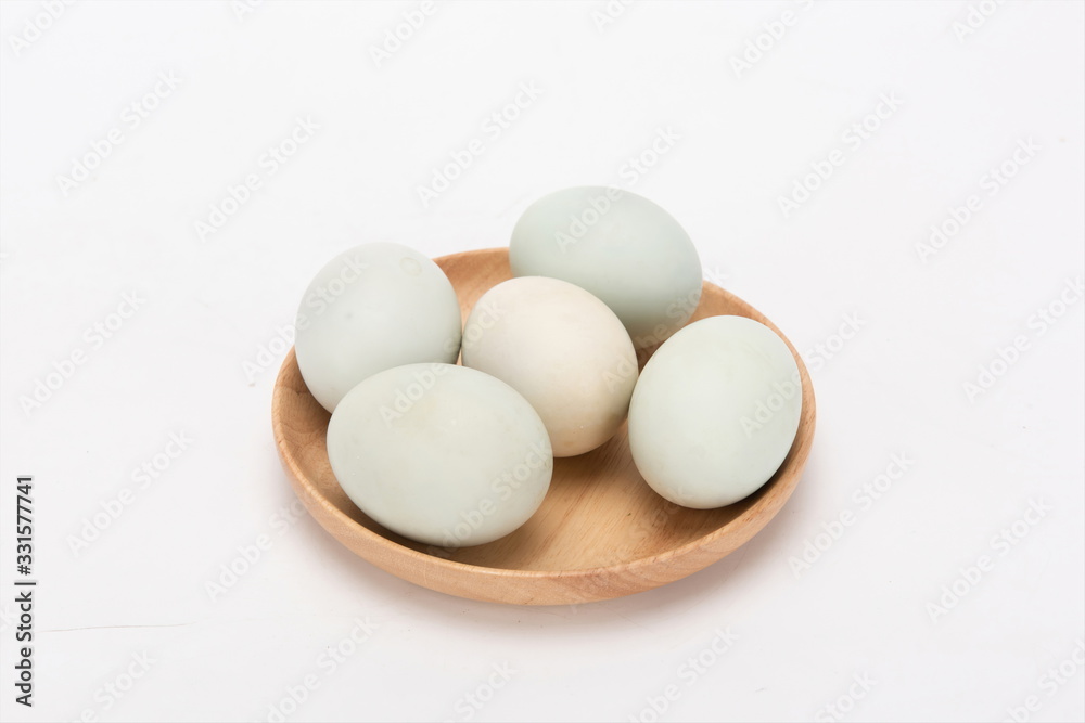 A few duck eggs are placed on a wooden plate, isolated against a white background A few duck eggs are placed on a wooden plate, isolated against a white background