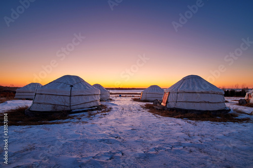 Mongolian yurts on the grassland in winter sunset.