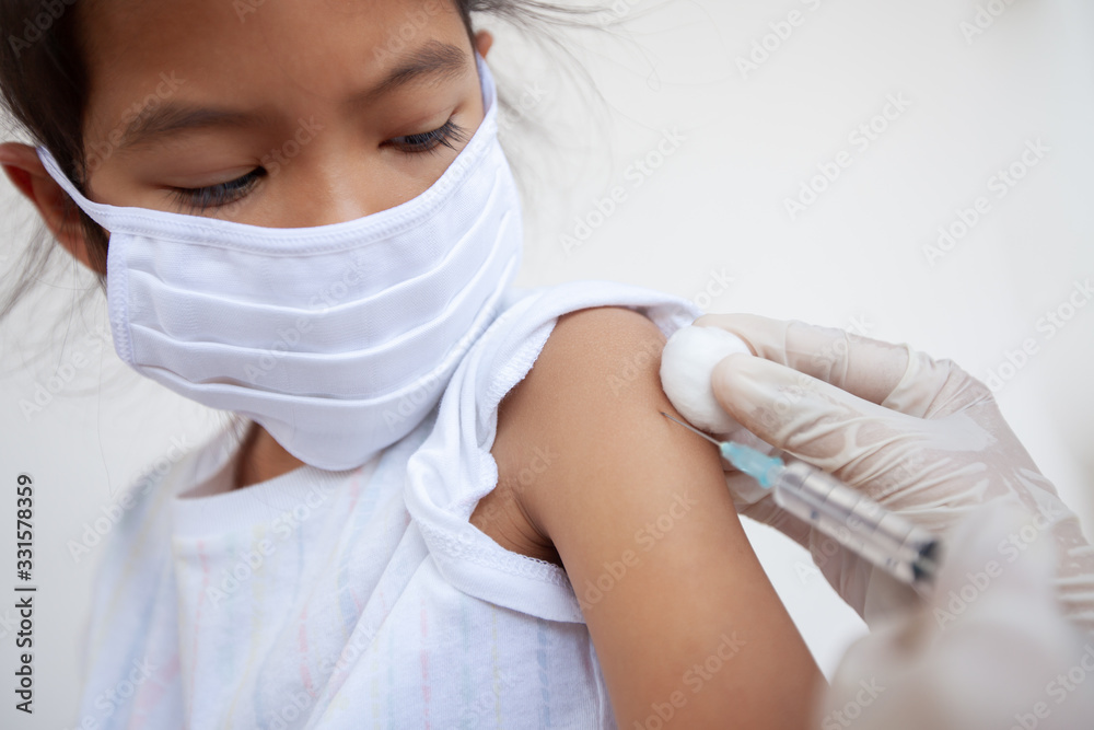 Doctor injecting vaccination on asian child girl arm. The child girl wearing protection mask for protect air smog pollution with PM 2.5 and Covid-19 virus. Healthy and medical concept. Doctor injecting vaccination on asian child girl arm. The child girl wearing protection mask for protect air smog pollution with PM 2.5 and Covid-19 virus. Healthy and medical concept.
