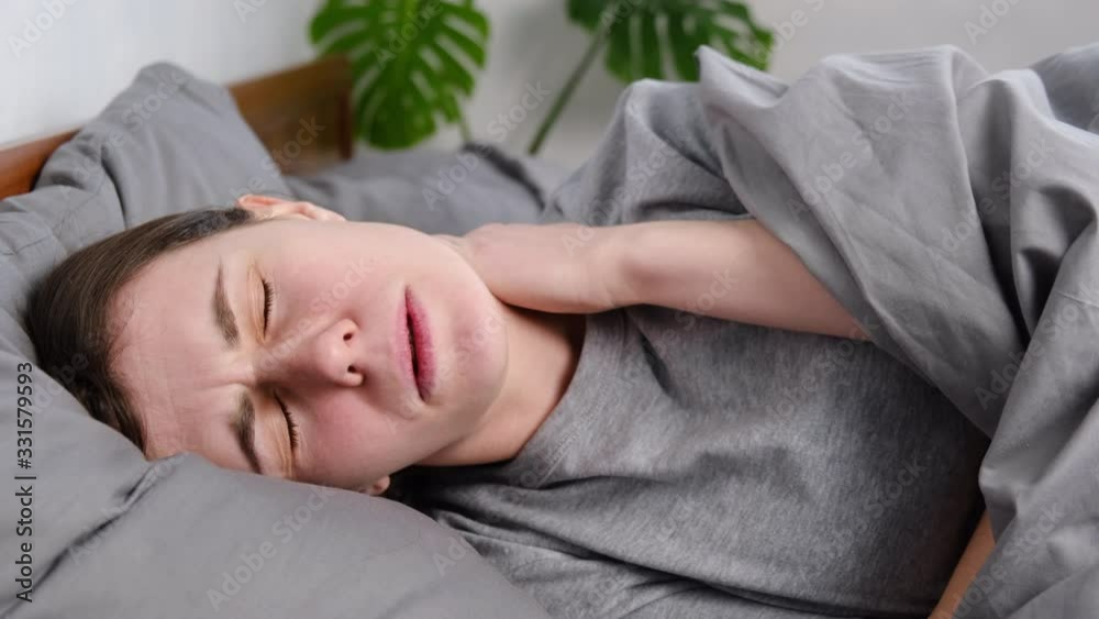 Tired upset young woman massage tense neck muscles lying in bed, stress relief, exhausted girl suffering from pain, feeling physics discomfort. Fibromyalgia concept Tired upset young woman massage tense neck muscles lying in bed, stress relief, exhausted girl suffering from pain, feeling physics discomfort. Fibromyalgia concept