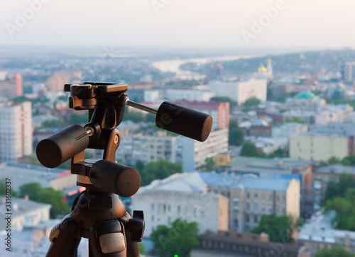 Tripod with a tripod head on the background of the city.
