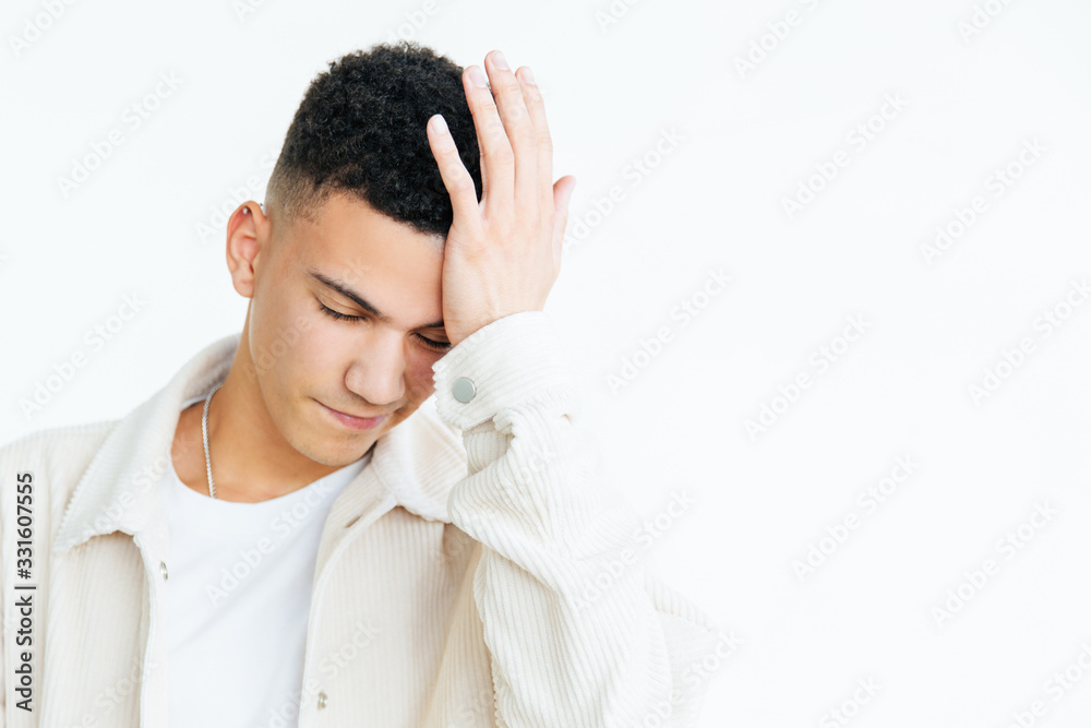 Frustrated young man with hand on forehead. Portrait of unhappy young man standing with hand on head isolated on grey background. Gesture concept Frustrated young man with hand on forehead. Portrait of unhappy young man standing with hand on head isolated on grey background. Gesture concept