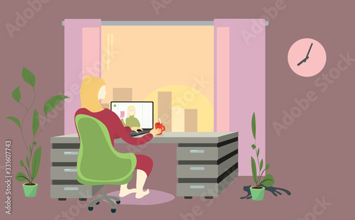 a woman in chair at the table is negotiating a video call against the sunset in the window. later time for remote work