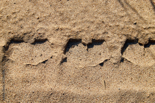 Tyre prints on the yellow sand. Nature background or texture